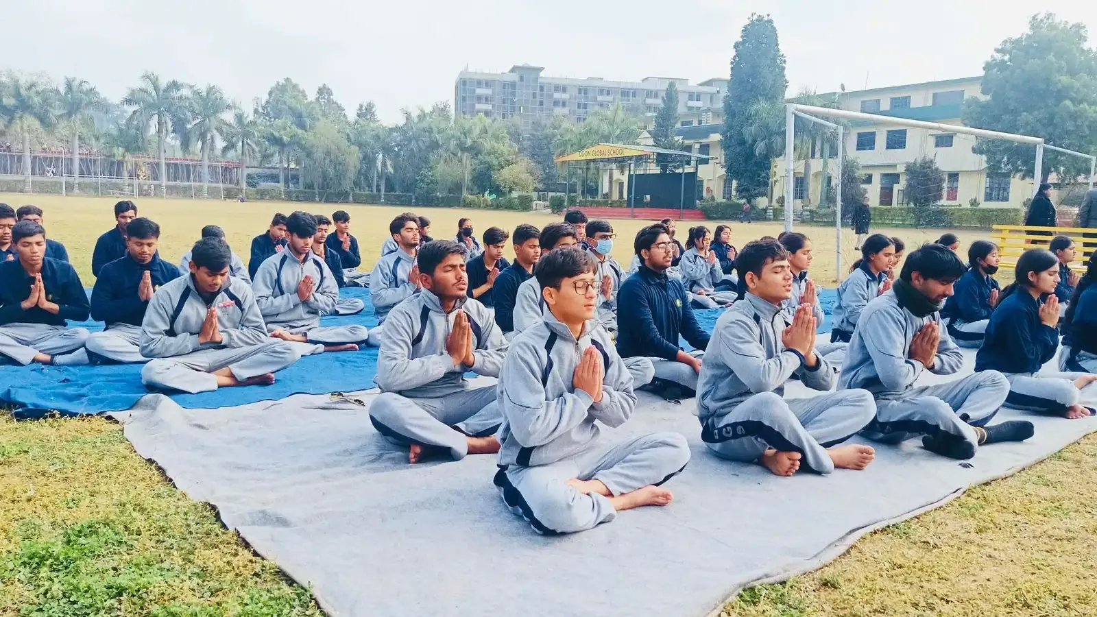 स्कूल के मैदान में योग सत्र में बैठे दून ग्लोबल स्कूल के विद्यार्थी