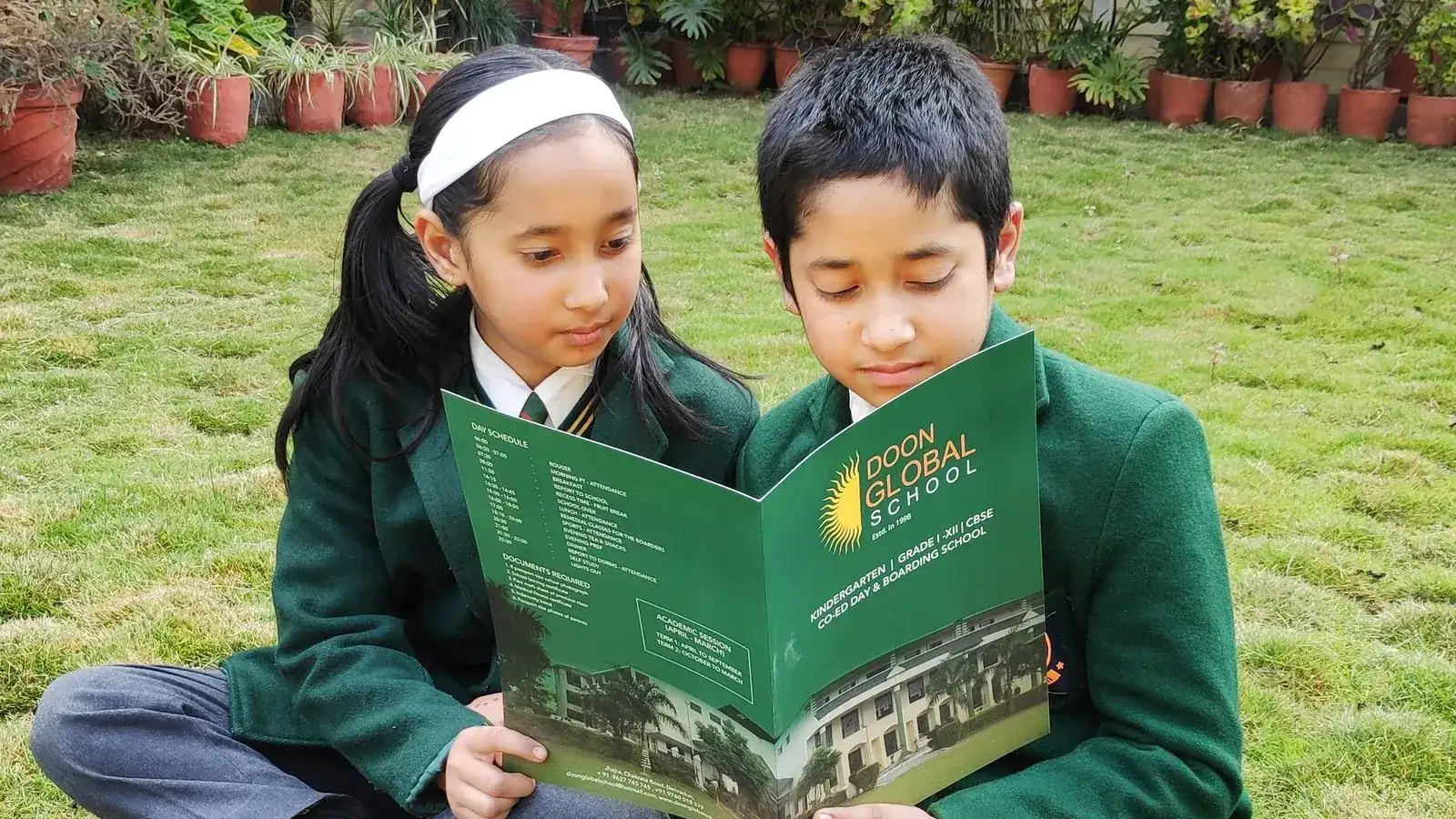 Two Doon Global School students reading together on the school lawn