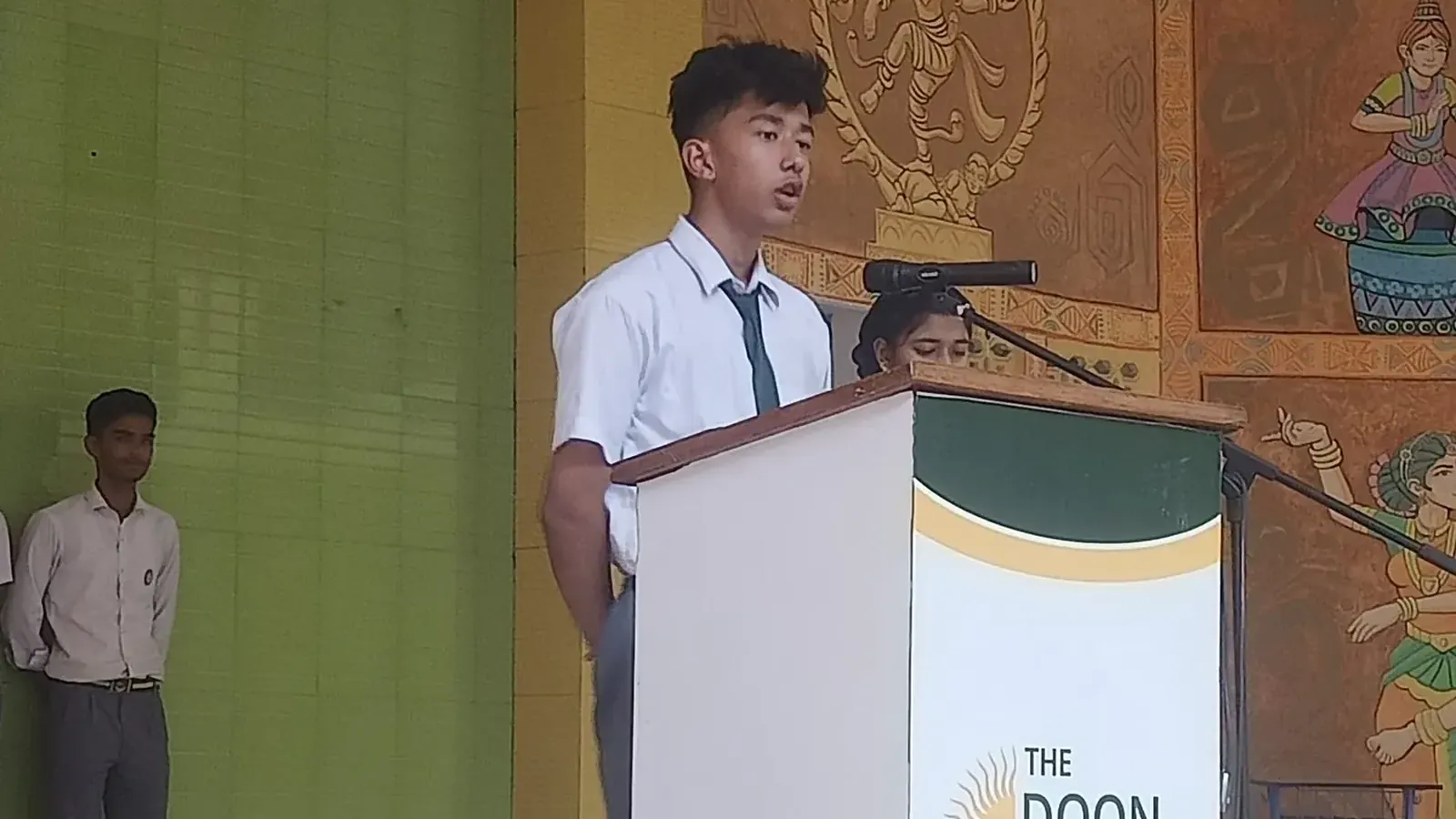 A Doon Global School student speaking at the lectern in the school's assembly area