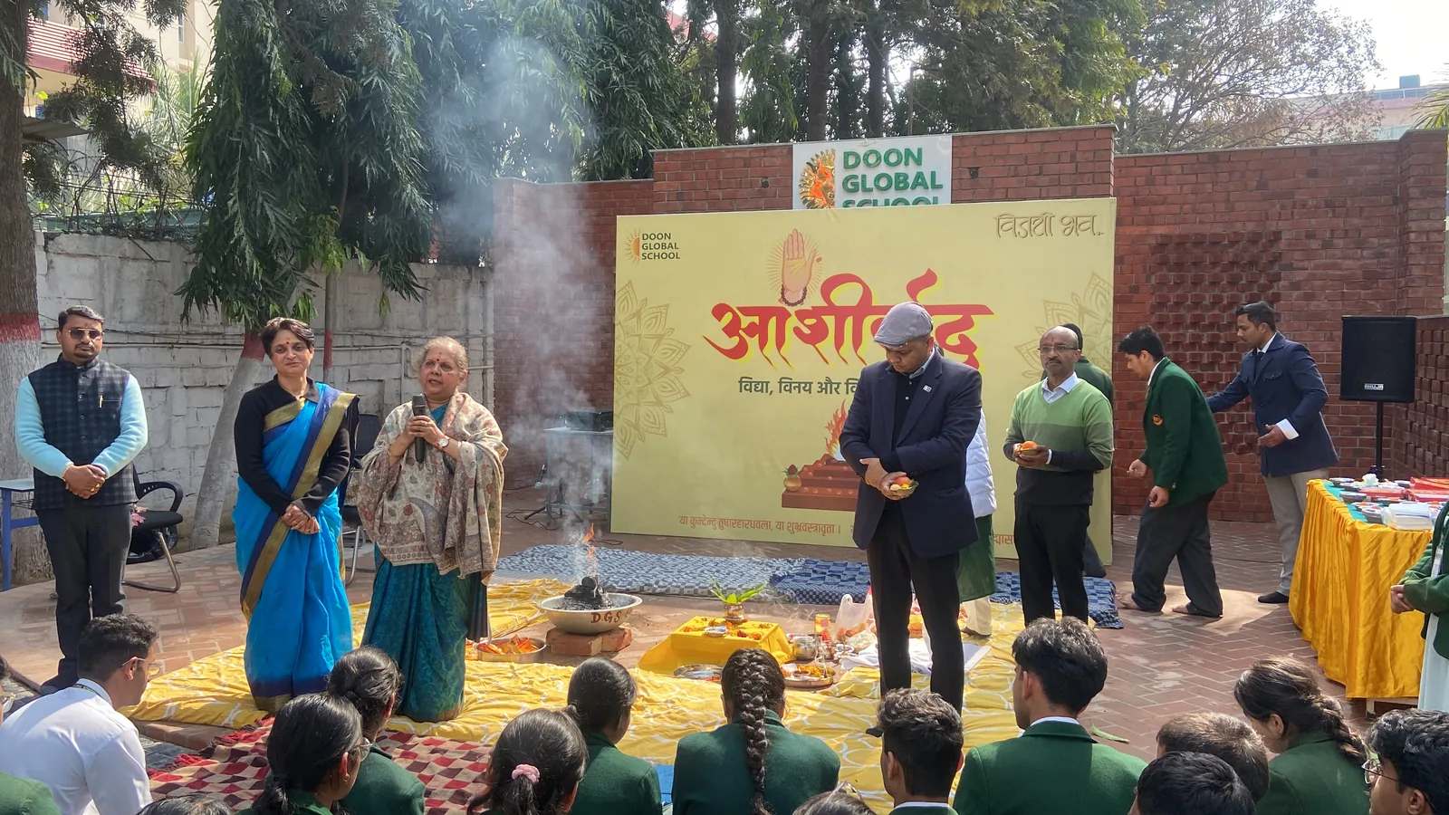 Students and teachers gathered around the havan at the Ashirwad ceremony in front of the school backdrop