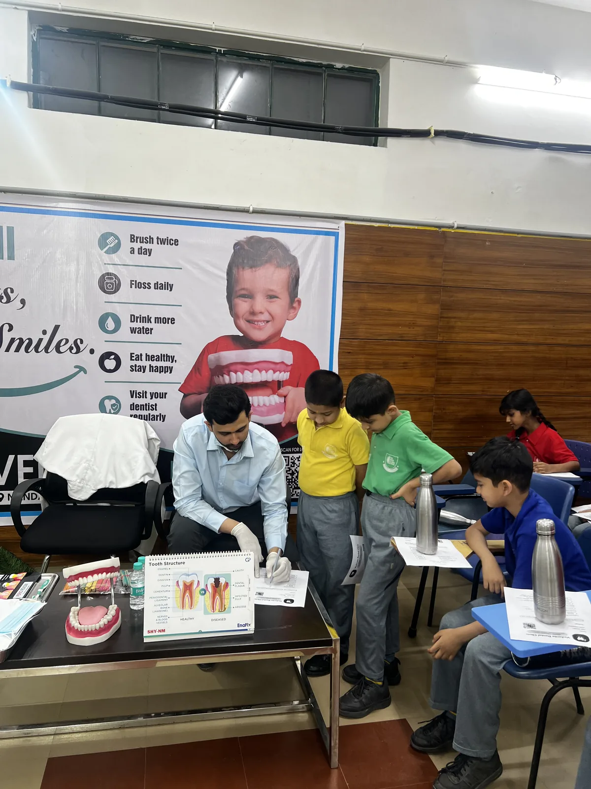 A dentist showing students how to brush using a model of teeth at the dental camp