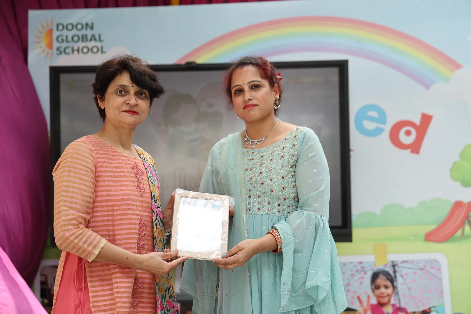 A certificate being presented on stage in front of the rainbow backdrop