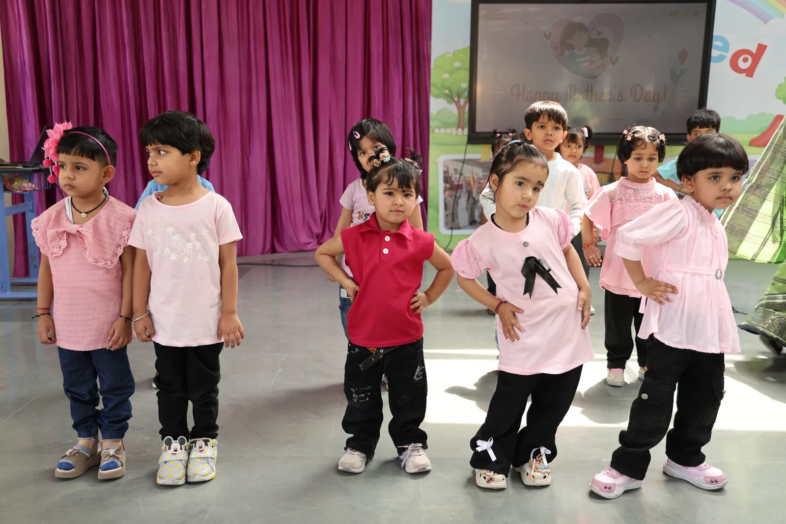 Young students in pink t-shirts performing a dance on stage