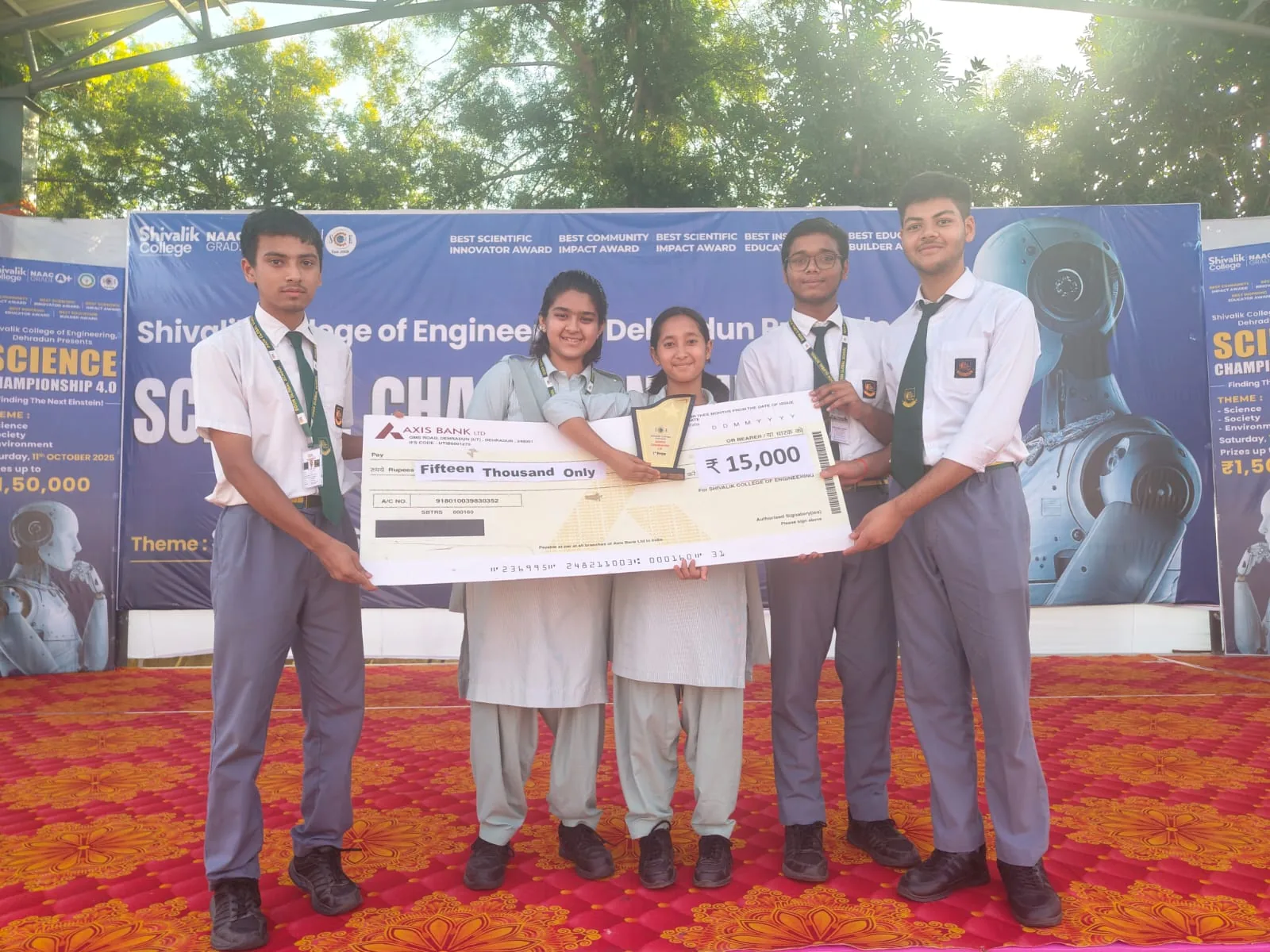 DGS students holding a prize cheque on stage at the science championship at Shivalik College of Engineering