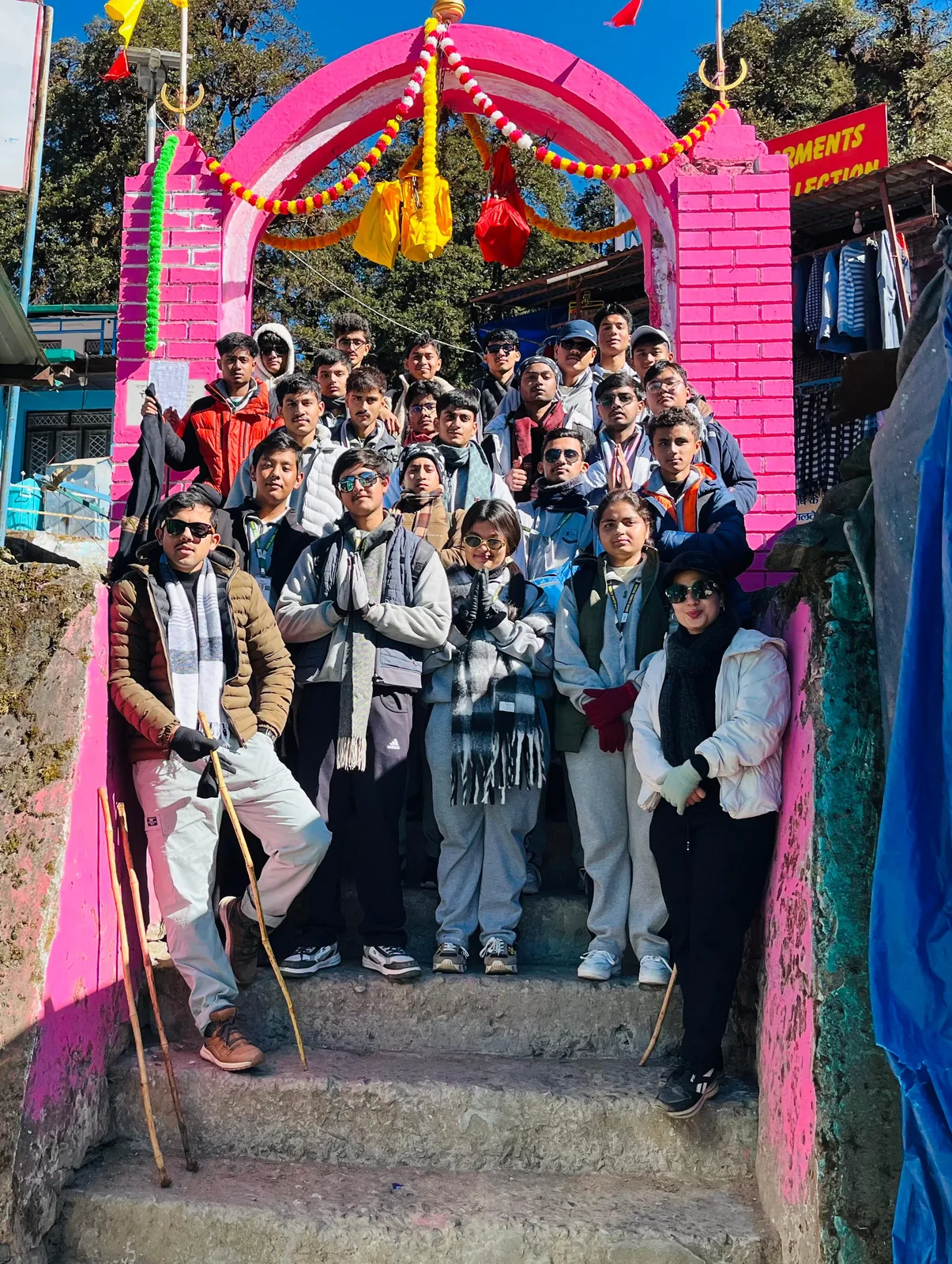 Students gathered under a pink decorated arch at the start of the trek