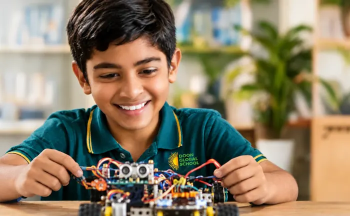 A smiling student wiring a small robot