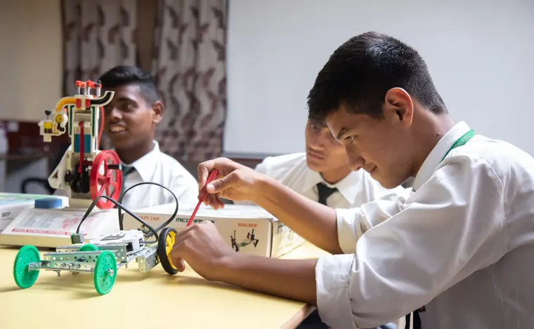 Students building a small robot car in a school workshop