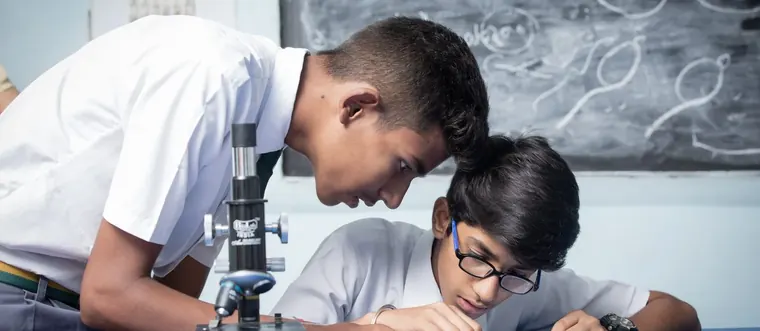Two students looking through a microscope in the school laboratory