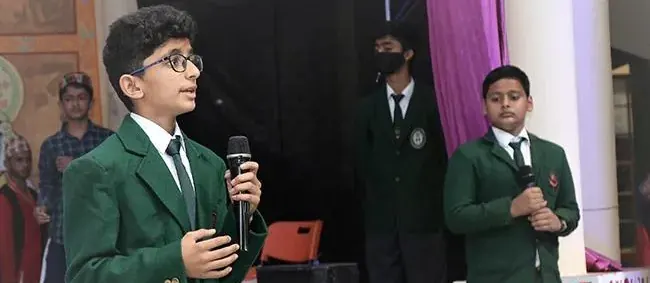 A student in the school blazer speaking into a microphone on stage